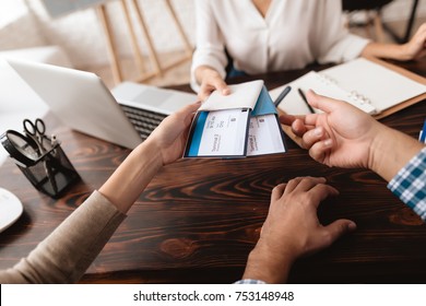 A young man and a woman came to the travel agency. They want to go on a trip during their holidays. The agent gives them tickets. - Powered by Shutterstock