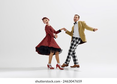 Young man and woman, couple dressed in retro-inspired outfits joyfully dancing together isolated over white studio background. Concept of art, retro and vintage, hobby, entertainment, 20s - Powered by Shutterstock