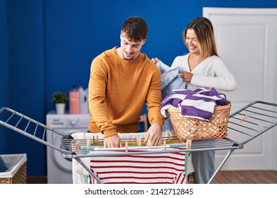 Young man and woman couple hanging clothes on clothesline at laundry room