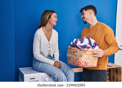 Young Man And Woman Couple Washing Clothes At Laundry Room