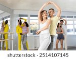 Young man and young woman dance ballroom dance waltz in studio