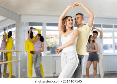 Young man and young woman dance ballroom dance waltz in studio - Powered by Shutterstock