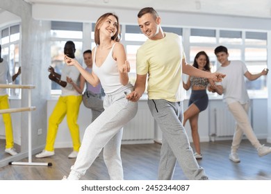 Young man and young woman dance energetic twist dance in studio - Powered by Shutterstock