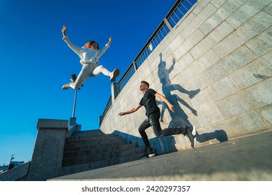 Young man and woman doing parkour in the city on sunny day - Powered by Shutterstock