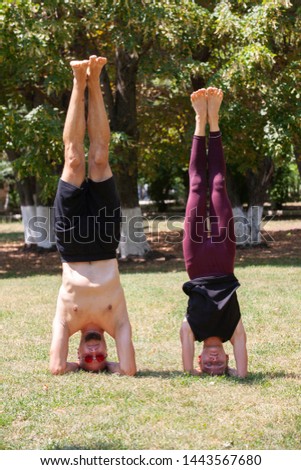 Young man and woman doing yoga in the sunny summer park. Portrait
