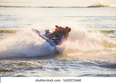 Young Man And Woman Drive On The Jetski Above The Water At Sunset .silhouette. Spray.