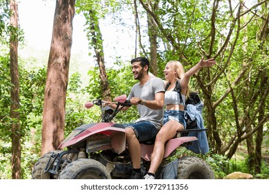 Young man and woman driving off road adventure with happy and having fun. Couple riding on ATV bike or quad bike on road along forest trail on mountain. Camping, jungle adventure concept