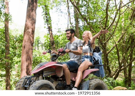 Young man and woman driving off road adventure with happy and having fun. Couple riding on ATV bike or quad bike on road along forest trail on mountain. Camping, jungle adventure concept