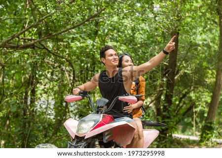 Young man and woman driving off road adventure with happy and smiling. Couple riding on ATV bike or quad bike on road along forest trail on mountain. Camping, jungle adventure concept