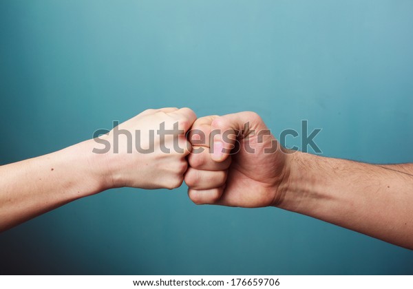 Young man and woman are\
fist bumping
