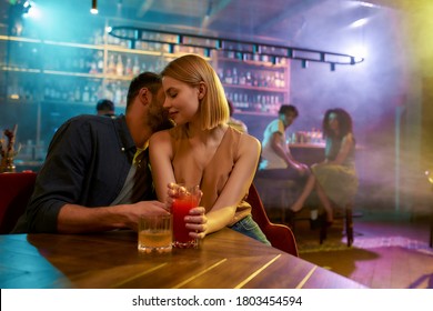 Young man and woman flirting in the bar, enjoying drinks and conversation. Love, couple, romance concept. Selective focus. Horizontal shot