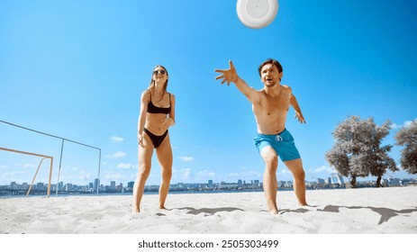 Young man and woman, friends playing dynamic frisbee game on beach by the river under clear blue sky. Hot summer days. Concept of sport, summer activity, leisure games, friendship - Powered by Shutterstock