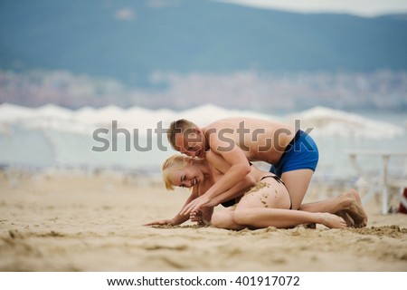 Young man and woman having fun on the sea beach