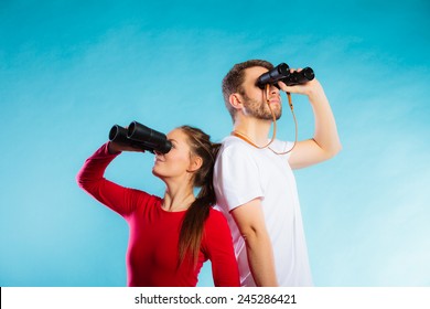  Young man and woman lifeguards on duty or tourist couple looking through binocular studio shot on blue