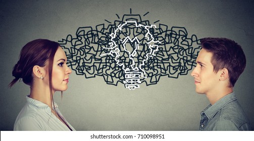 Young man and woman looking at each other exchanging their thoughts coming up together with an idea light bulb  - Shutterstock ID 710098951