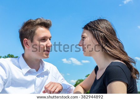 Young man and woman in love talking outdoors with blue sky