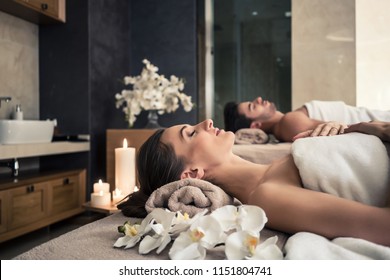 Young Man And Woman Lying Down On Massage Beds At Asian Luxury Spa And Wellness Center