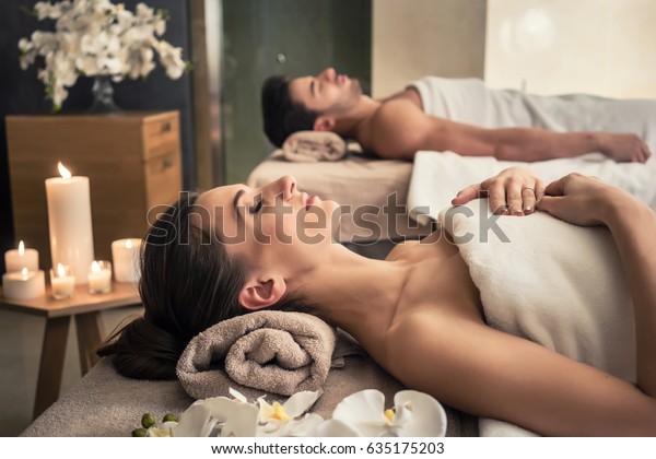 Young man and woman lying down on massage\
beds at Asian luxury spa and wellness\
center