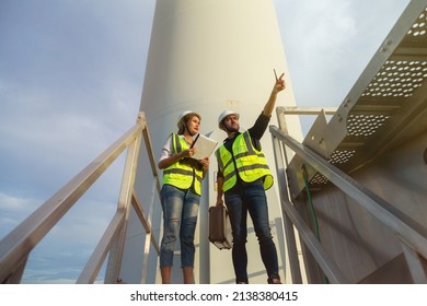 Young Man And Woman Maintenance Engineer Team Working In Wind Turbine Farm. Generator Station, Renewable Energy