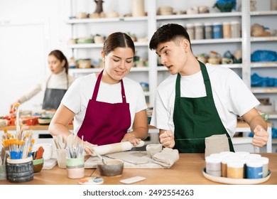 Young man and young woman making pottery from clay in workshop - Powered by Shutterstock