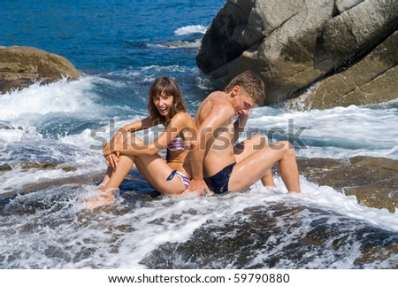 The young man and woman on reefs in surf.