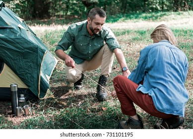 Young man and woman pitching a tent in the woods - Powered by Shutterstock