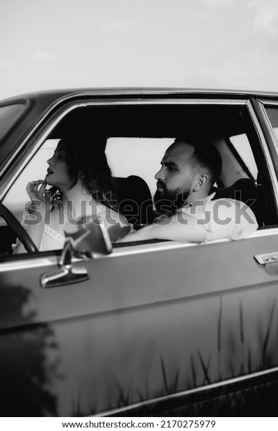 A young
man with a young woman in a red retro car. A couple in love travels
in an old vintage car. Black and white.
