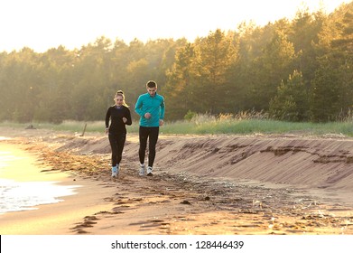 Young man and woman running along the waterfront