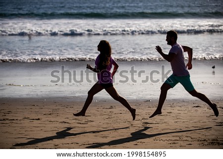 Young man and woman running jogging along the sea. Couple running on beach.