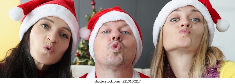 Young man and woman in santa hats holding glasses of champagne and blowing kiss - Powered by Shutterstock