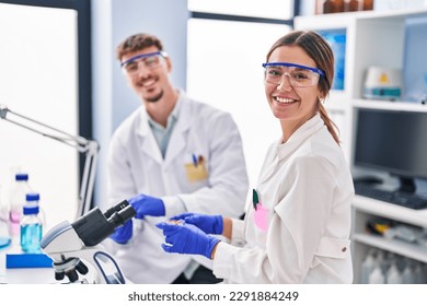 Young man and woman scientists workers using microscope at laboratory - Powered by Shutterstock