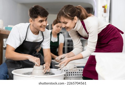 Young man and young woman sculpting pottery on potter's wheel in workshop - Powered by Shutterstock