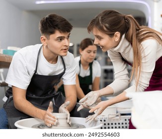 Young man and young woman sculpting pottery on potter's wheel in workshop - Powered by Shutterstock