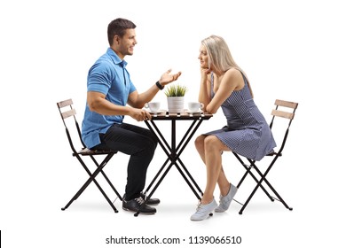 Young Man And A Young Woman Sitting At A Coffee Table And Talking Isolated On White Background