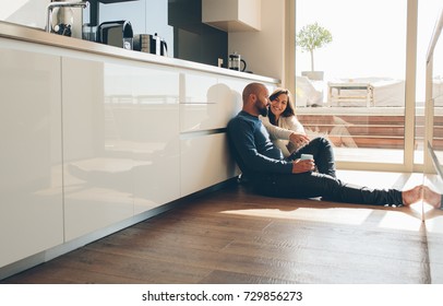 Young man and woman sitting on floor in kitchen and talking. Loving young couple spending time together at home. - Powered by Shutterstock