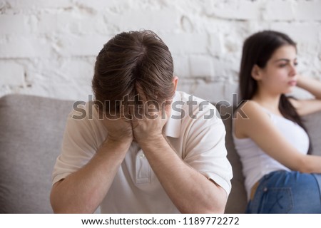 Young man and woman sitting on couch not talk, not looking of each other after quarrel at home. Millennial couple feels unhappy. Relations problems and difficulties, break up, misunderstanding concept