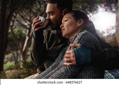 Young man and woman sitting outdoors. Relaxed young couple resting outdoors with man drinking coffee. - Powered by Shutterstock