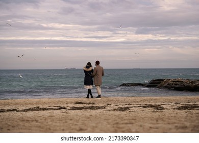 Young man and a young woman stand embracing on the Black Sea coast and look at the waves                        - Shutterstock ID 2173390347