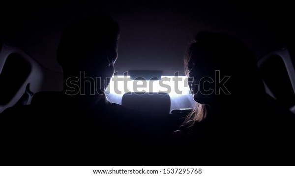 Young man and woman talking in automobile,\
driving to evening party, stars\
life