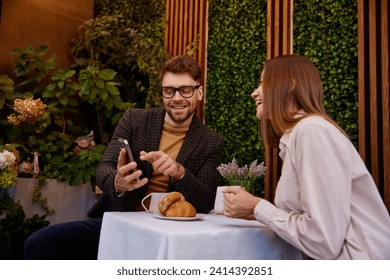 Young man and woman talking using mobile phone having business meeting in cafe - Powered by Shutterstock