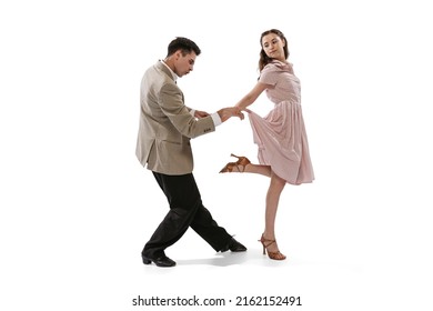 Young man and woman in vintage retro style outfits dancing social dance isolated on white background. Timeless traditions, 1960s american fashion style and art. Dancers look happy, delighted