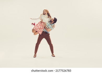 Young man and woman in vintage retro style outfits dancing social dance isolated on white background. Timeless traditions, 1960s american fashion style and art. Dancers look happy, delighted - Powered by Shutterstock