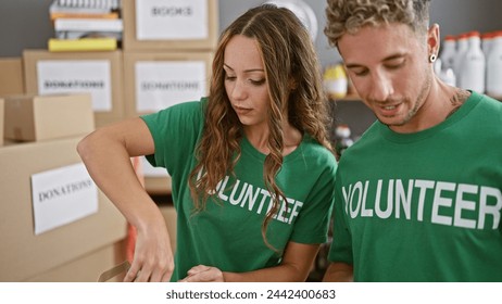 Young man and woman volunteers sort donations in a warehouse with cardboard boxes. - Powered by Shutterstock