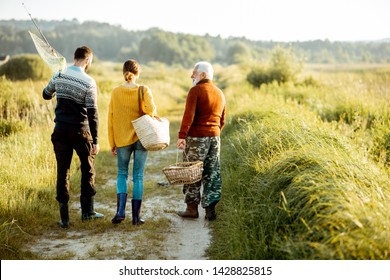 Young man and woman walking on the picnic with senior grandfather dressed in sweaters, spending a good time together on the nature - Shutterstock ID 1428825815