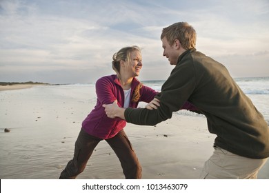Young man and woman wrestling at beach