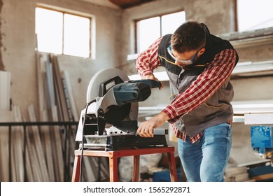 Young man work in home workshop garage with a grinder cuts metal bar - Powered by Shutterstock