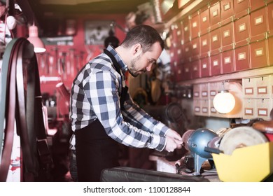 Young man worker working on belt buckle in leather workshop