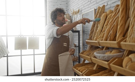 Young man working in a bakery, organizing and arranging freshly baked bread on wooden shelves in an indoor shop setting, wearing a brown apron and displaying hispanic features. - Powered by Shutterstock