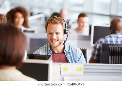 Young man working at a computer in a call centre - Shutterstock ID 314848493
