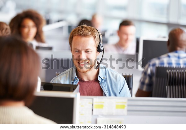 Young man\
working at a computer in a call\
centre